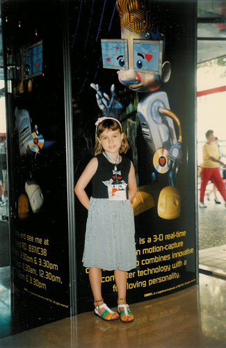 A child standing in front of the backlit COMPET stand poster at Cannes