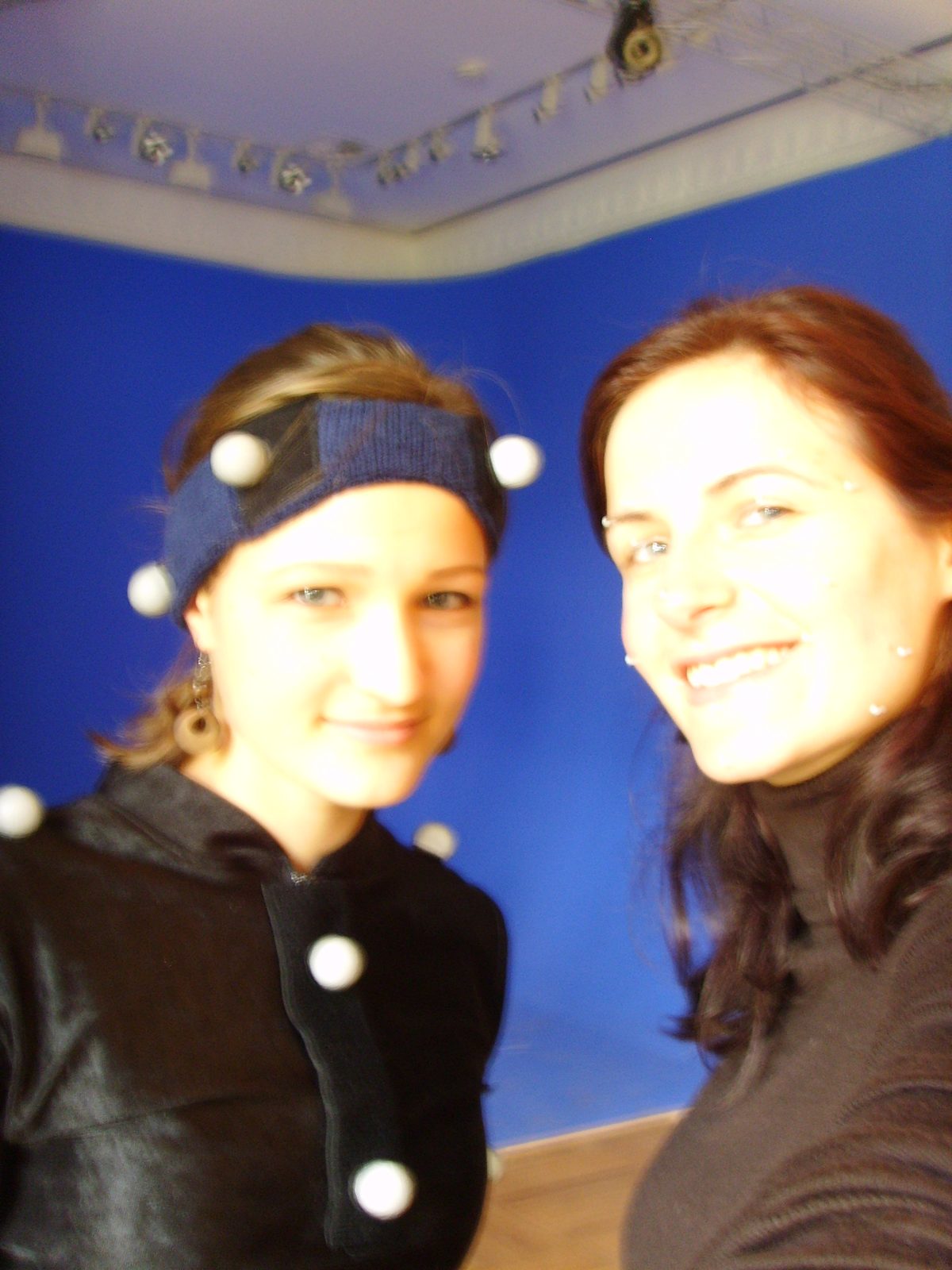 Two performers in the bluebox, one wearing body-tracking markers, one wearing facial markers